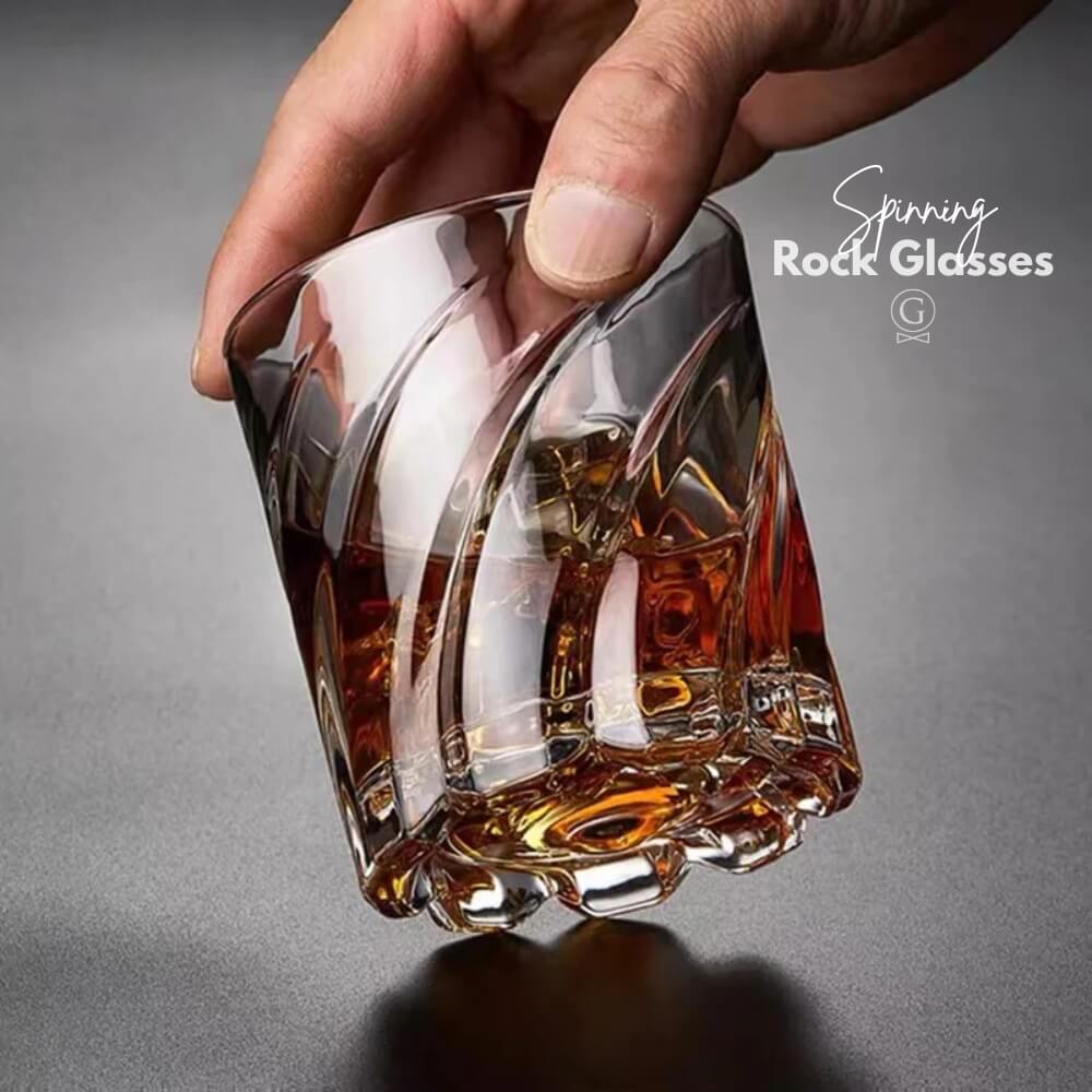 Hand holding a whiskey glass with a gray background
